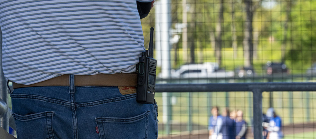 Man watching a baseball game with a walkie talkie on belt