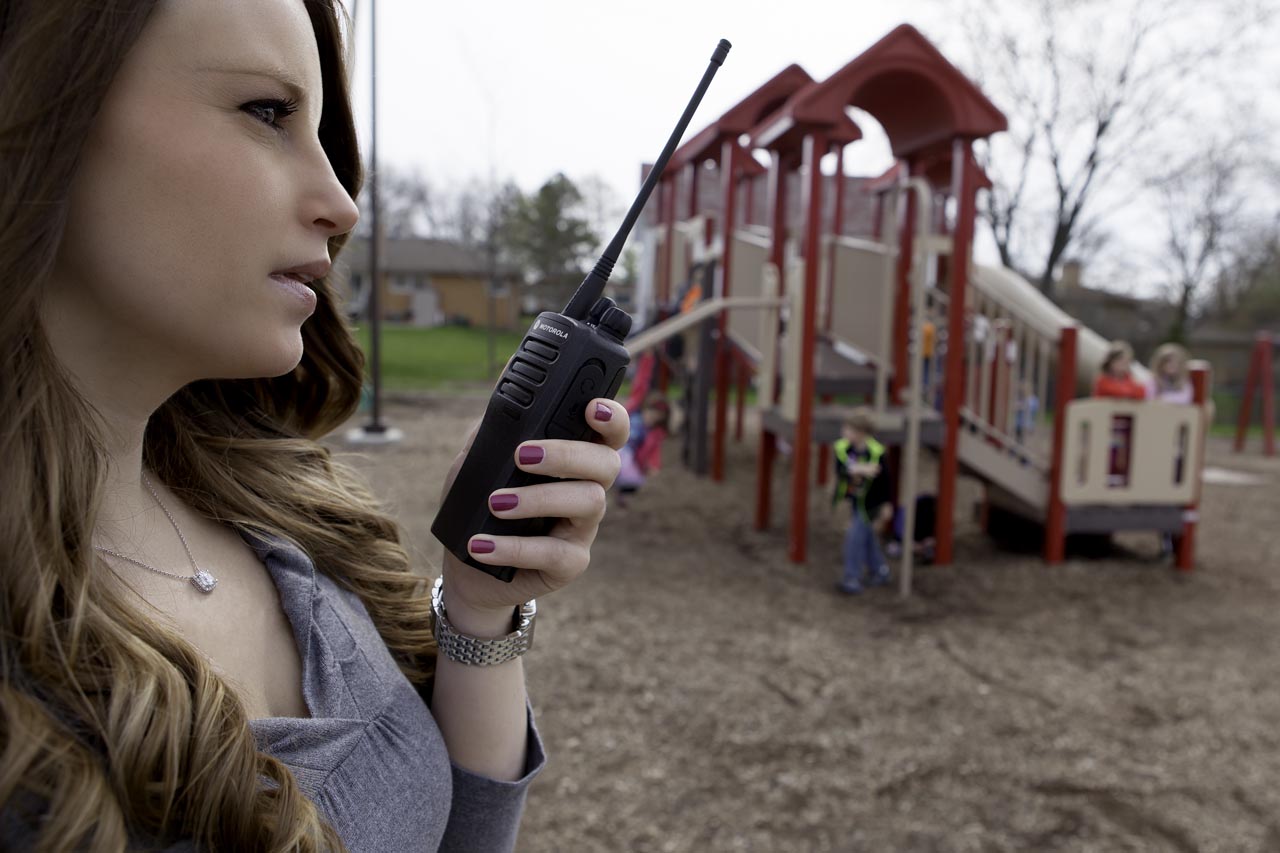 woman on playground holding a walkie talkie